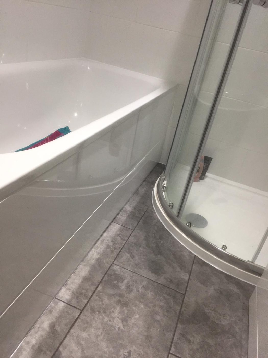 Bathroom with large-format grey tiles and curved shower screen